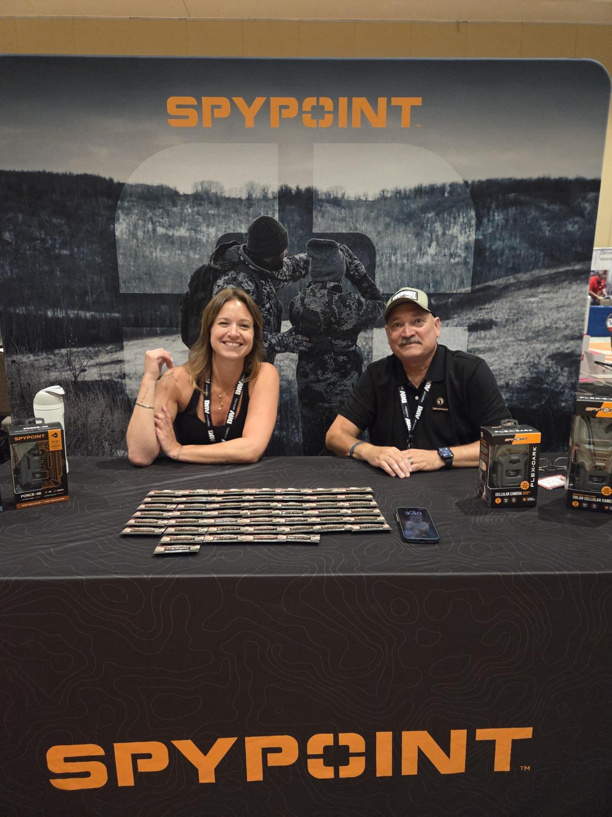 Blog-386_Image-3-SPYPOINT-Team-at-DAV-National-Convention SPYPOINT team members at the SPYPOINT booth with cellular trail cameras on display during the 2026 DAV National Convention.