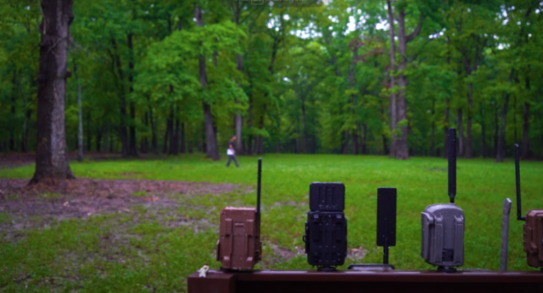 A man walking yards in front of a group of trail cameras