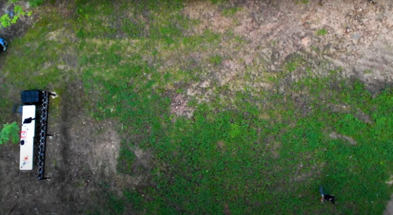 An aerial photo of a man walking many feet in front of a group of trail cameras